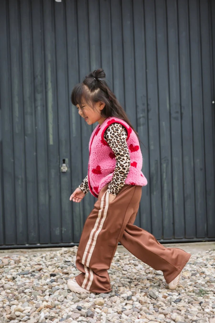 Kind trägt braune Hose und pinke Wollweste von Salty Stitch x Alwero