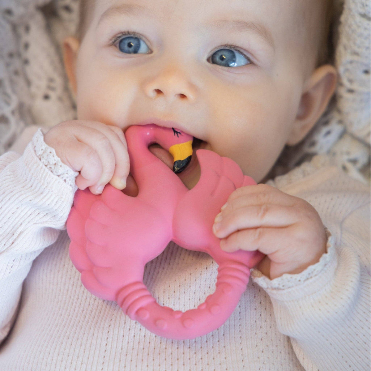 Baby met een roze flamingo bijtring van Natruba, gemaakt van natuurrubber