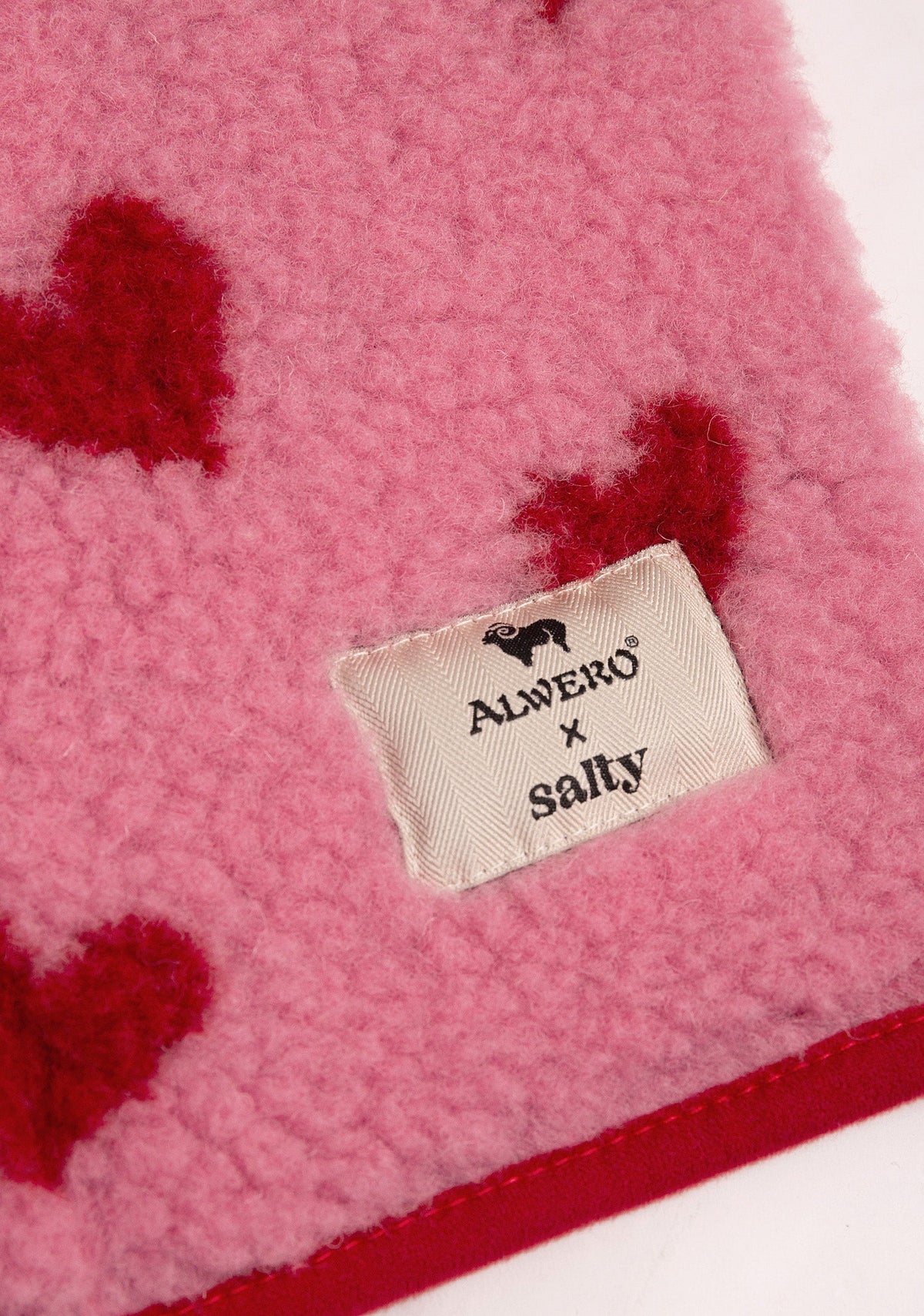 Detail der pinken Wollweste mit roten Herzen von Salty Stitch