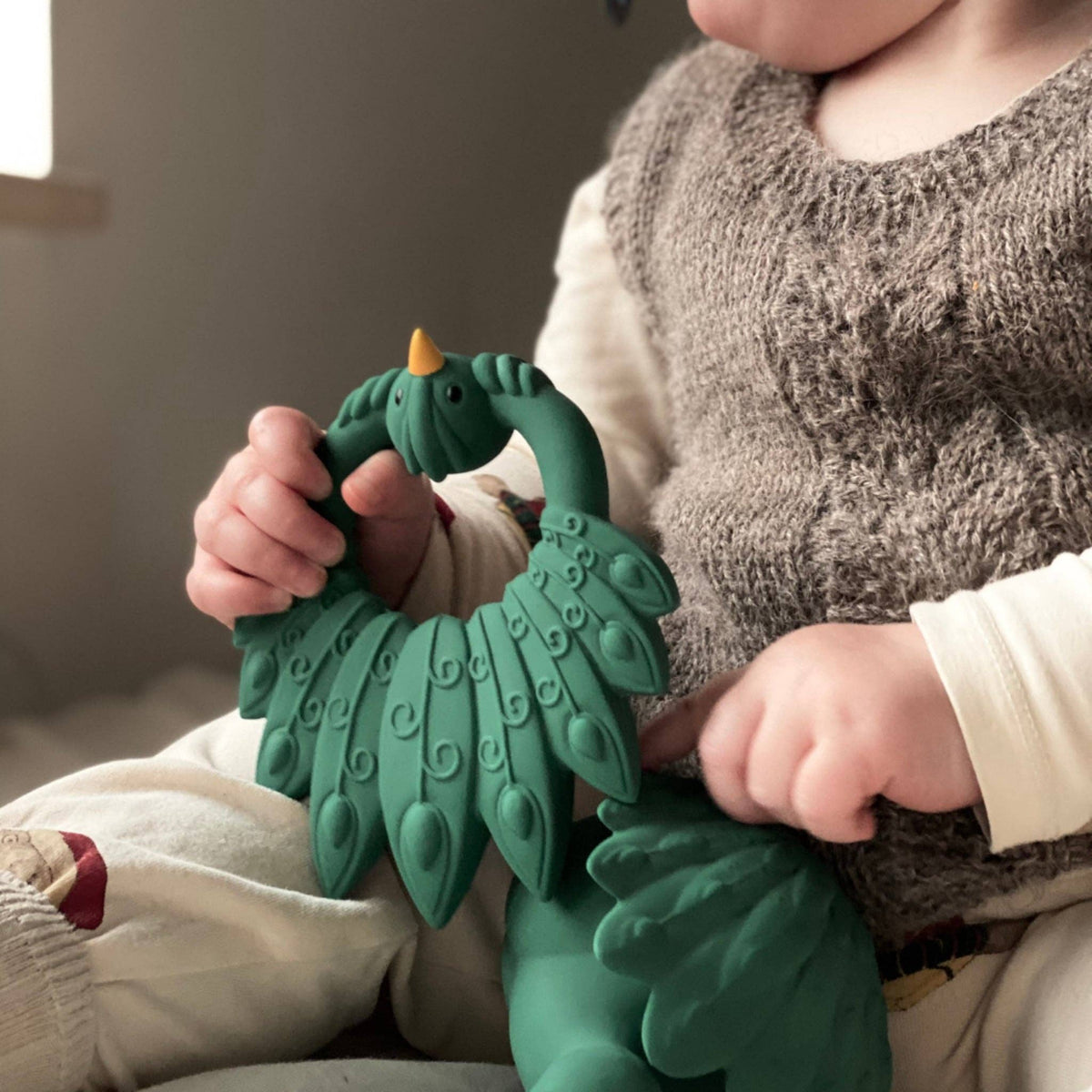 Baby met een groen pauw bijtring van Natruba, gemaakt van natuurrubber