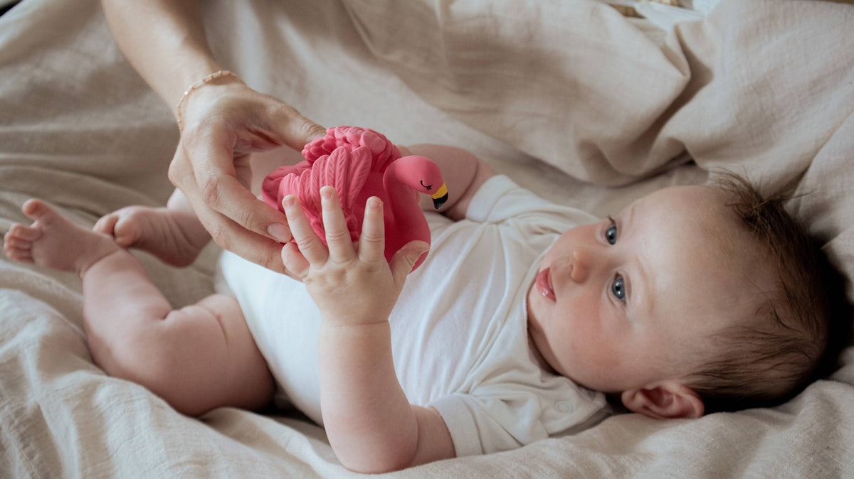 Baby met een roze flamingo badspeeltje van Natruba, gemaakt van natuurrubber