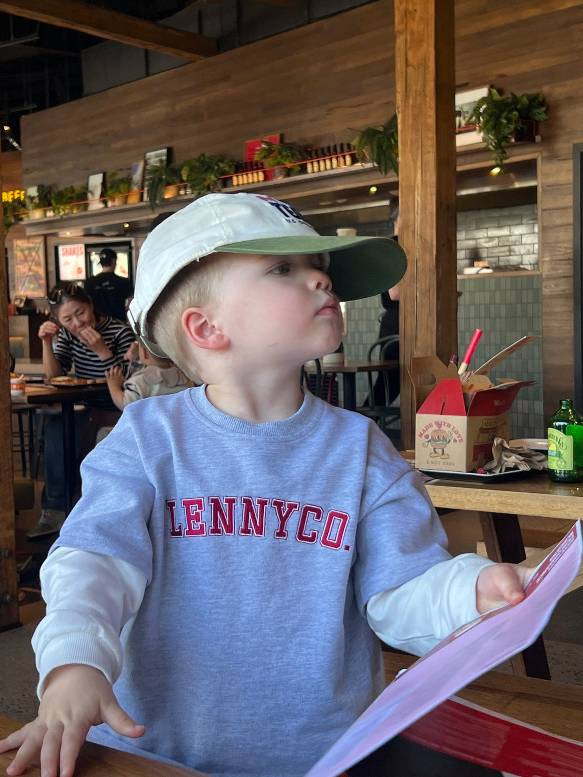 Grey layered top with white sleeves by Lennyco worn in a café